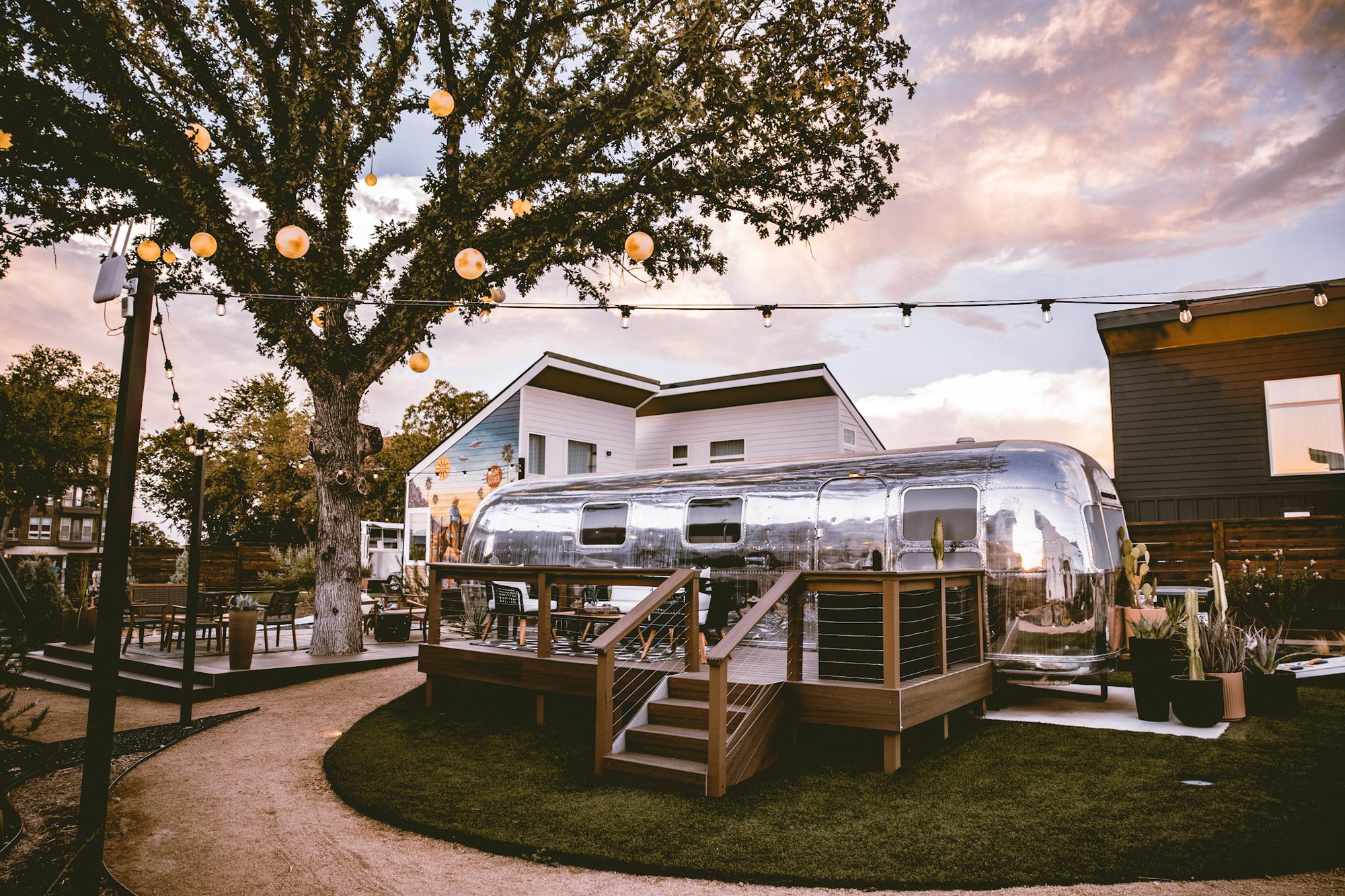 A vintage Airstream suite and its private deck under string lights at golden hour, Hotel SOMA Fort Worth