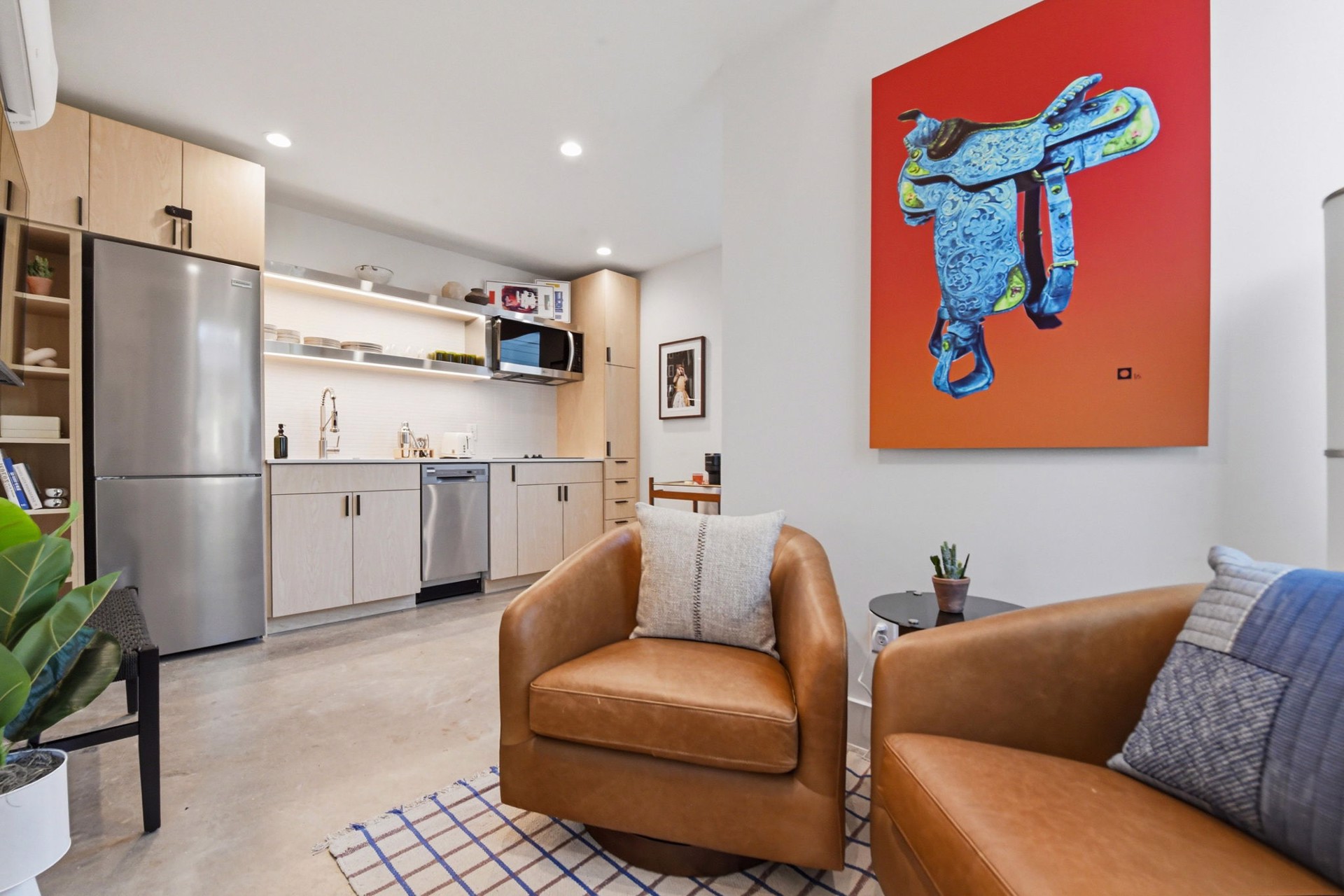 A bold blue Western saddle painting on a red wall in a SOMA casita — from the William Campbell Gallery collection