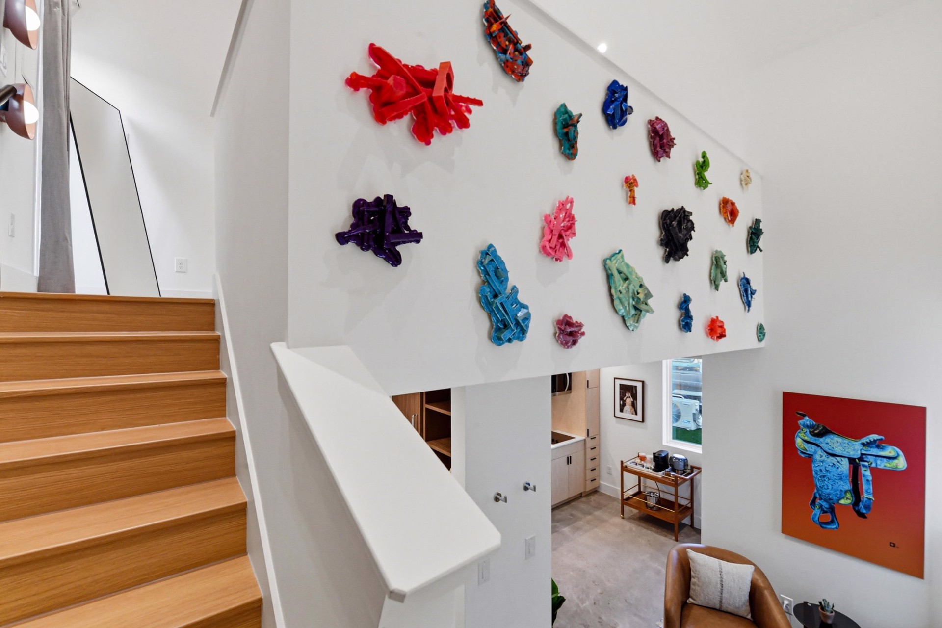 A wall of colorful sculptural works above the casita stairwell