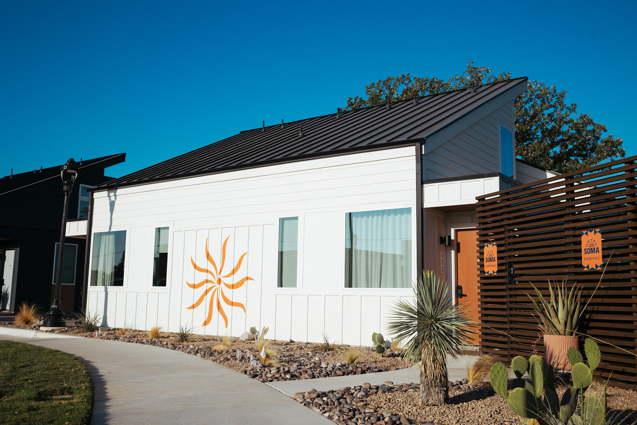 White casitas with the orange SOMA pinwheel mural and black metal roofs in Fort Worth