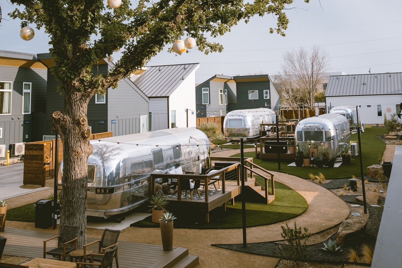 An elevated view over the Hotel SOMA courtyard — Airstream suites, winding lawn paths and casitas beneath the live oak in Fort Worth