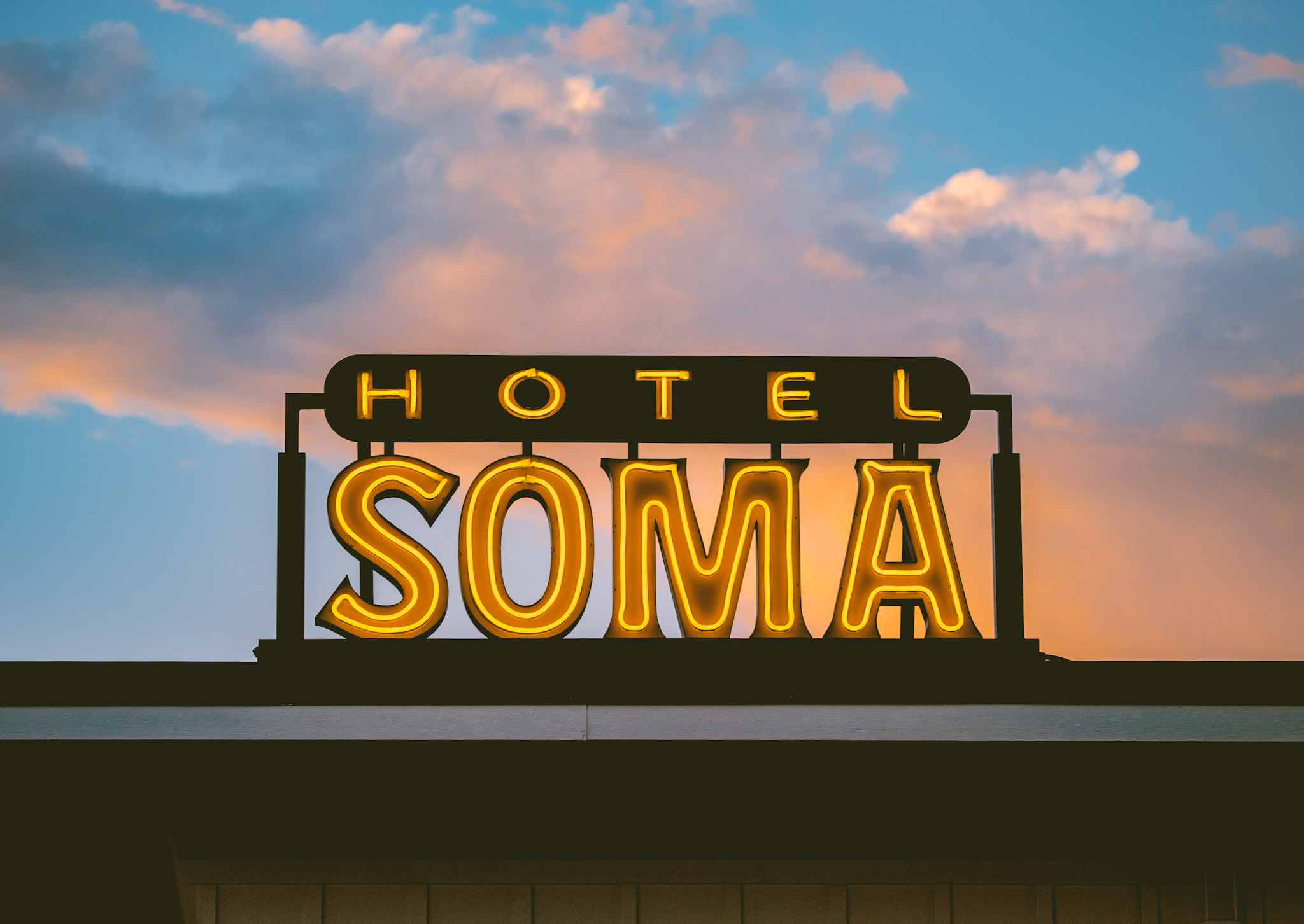 The Hotel SOMA neon sign lit against a pink Fort Worth sunset